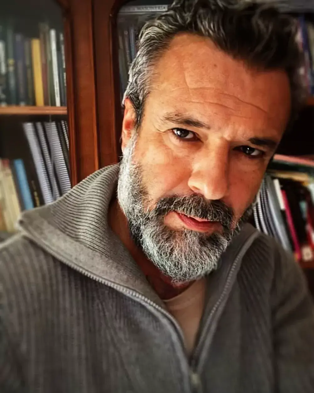 Il Maestro Humberto Mendes nel suo studio, davanti alla libreria