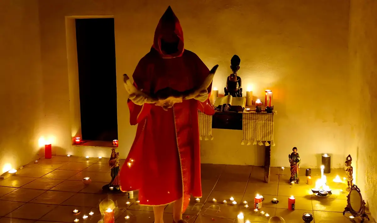 Il Maestro in tunica rossa nel tempio, circondato dai lumi