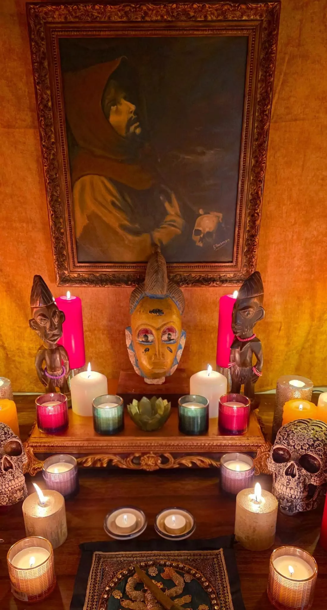 La maschera rituale e le statue africane sotto il dipinto del santo